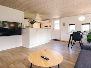 A modern kitchen with white cabinets, a wooden ceiling, and a dining area with a table and chairs. - 4 Star Holiday Home in Lokken (Lokken)