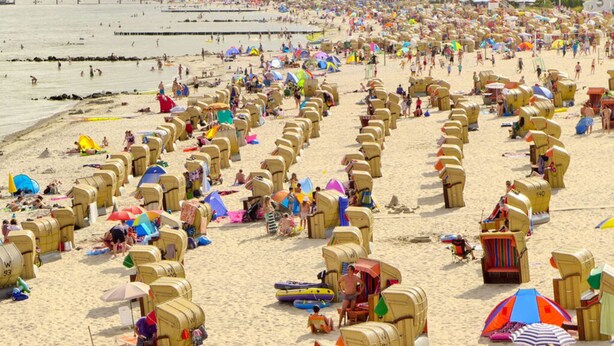 A beach with numerous sun loungers and umbrellas, a pier in the background, and a crowd of people. - "country House" Modern Retreat (Kellenhusen)