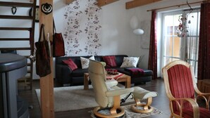 A living room with a sofa, armchairs, a coffee table, and a staircase.