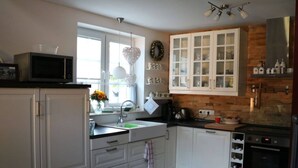A modern kitchen with white cabinetry, a built-in oven, and a microwave on the countertop.