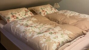 A bedroom with a bed, floral bedding, and a bedside lamp.