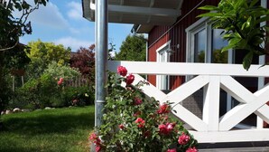 Una casa con cerca blanca y un jardín de flores rosadas.
