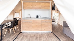 A compact kitchen with wooden cabinets, a sink, and a dining area with chairs. - Nice Safari Tent With Airco (Kotschach-Mauthen)