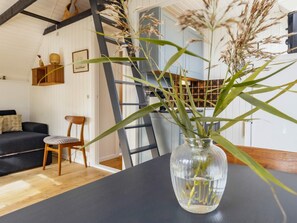 A room with a wooden floor, a black table, a clear vase with plants, a wooden chair, and a staircase. - 4 Person Holiday Home in Karrebaeksminde (Karrebæksminde)