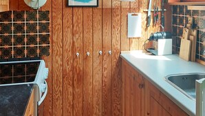 A kitchen with wooden cabinets, a tiled backsplash, and a countertop with a sink. - 4 Person Holiday Home in Karrebaeksminde (Karrebæksminde)