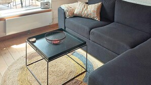 Un salon moderne avec une table basse noire, un canapé gris et un coussin décoratif à motifs.