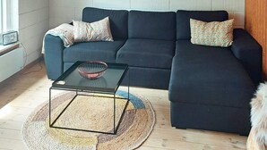 A modern living room with a dark sofa, a glass coffee table, and a woven rug. - 4 Person Holiday Home in Karrebaeksminde (Karrebæksminde)