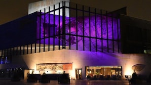A modern building with a large glass facade and a purple-lit interior. - "loft" Portmarina 26 (Bremerhaven)