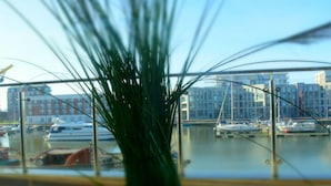 A view of a marina with boats docked, a glass railing, and buildings in the background. - "loft" Portmarina 26 (Bremerhaven)