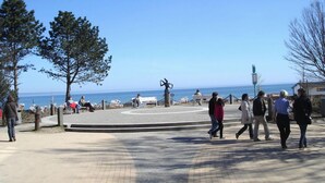 A public square with a clear view of the sea, a statue, and people walking. - Kurpark Residence Spot (Timmendorfer Strand)