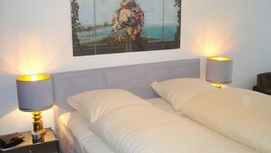 A hotel room with a bed, two bedside lamps, a nightstand with a phone, and a wall-mounted painting. - Kurpark Residence Spot (Timmendorfer Strand)