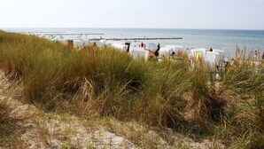 A beach with white tents and a pier extending into the water. - Lake View Modern Retreat (Insel Poel)