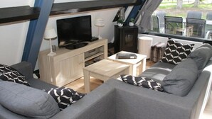 Un espace de vie moderne comprenant un canapé, une table basse, un téléviseur et une cheminée.