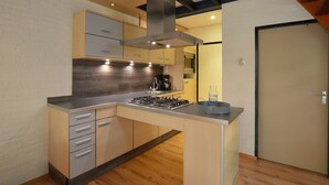 Une cuisine moderne dotée d’un îlot central, de meubles de rangement intégrés et d’une hotte en acier inoxydable.