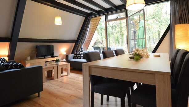 Une chambre moderne de style loft, avec des poutres apparentes, un coin repas et un téléviseur.