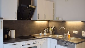 A modern kitchen with white cabinets, a built-in oven, a dishwasher, a stove, and a sink. - Beach Whispers Modern Retreat (Garding)
