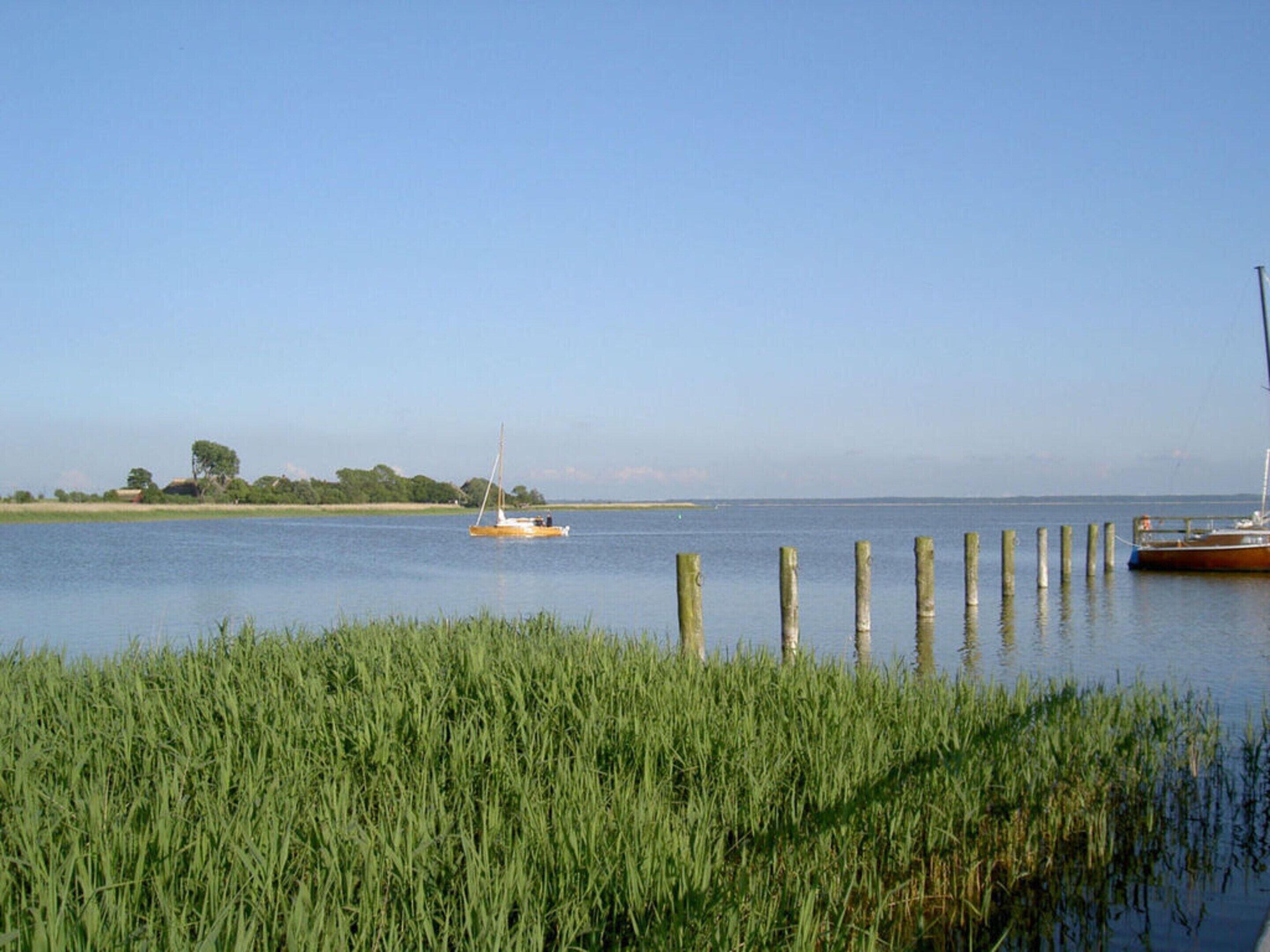 Una masa de agua tranquila con un velero y un barco amarrado.