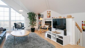 A modern living room with a sofa, a coffee table, a TV, and a bookshelf. - 8 Person Holiday Home on a Holiday Park in Bogense (Bogense)