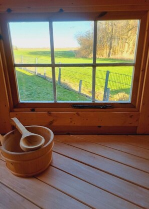 A wooden cabin with a large window overlooking a fenced field. - Holiday Home Coastal Dream (Brodersby)