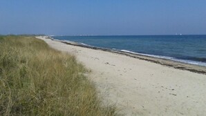 Ein sandiger Strand mit blauem Himmel und ruhiger See.