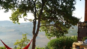 A hammock tied to a tree, a stone wall, and a view of a valley. - Cypressa Modern Retreat (Montefiore dell'Aso)