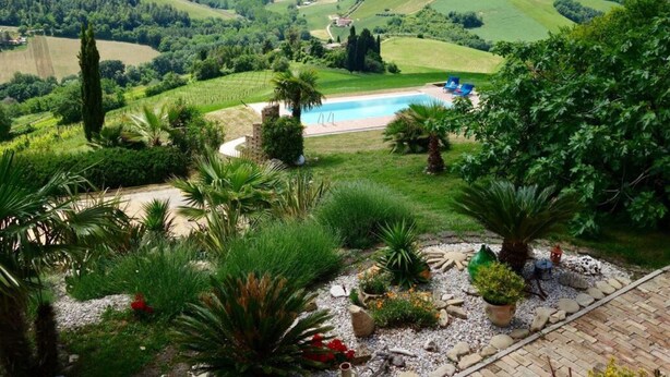 A lush garden with a swimming pool, surrounded by rolling hills and a clear sky. - Cypressa Modern Retreat (Montefiore dell'Aso)