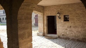 Un corredor de piedra con arco, una puerta y un farol en la pared.