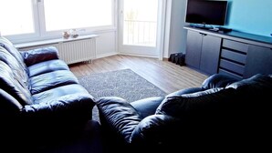 Ein Wohnzimmer mit einer Couch, einem Fernseher und einer Heizung.