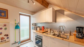 Una cocina moderna con armarios blancos, un lavamanos de acero inoxidable y una cafetera.