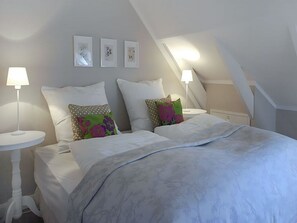 Une chambre à coucher comprenant un lit, deux tables de chevet et trois cadres photo accrochés au mur.