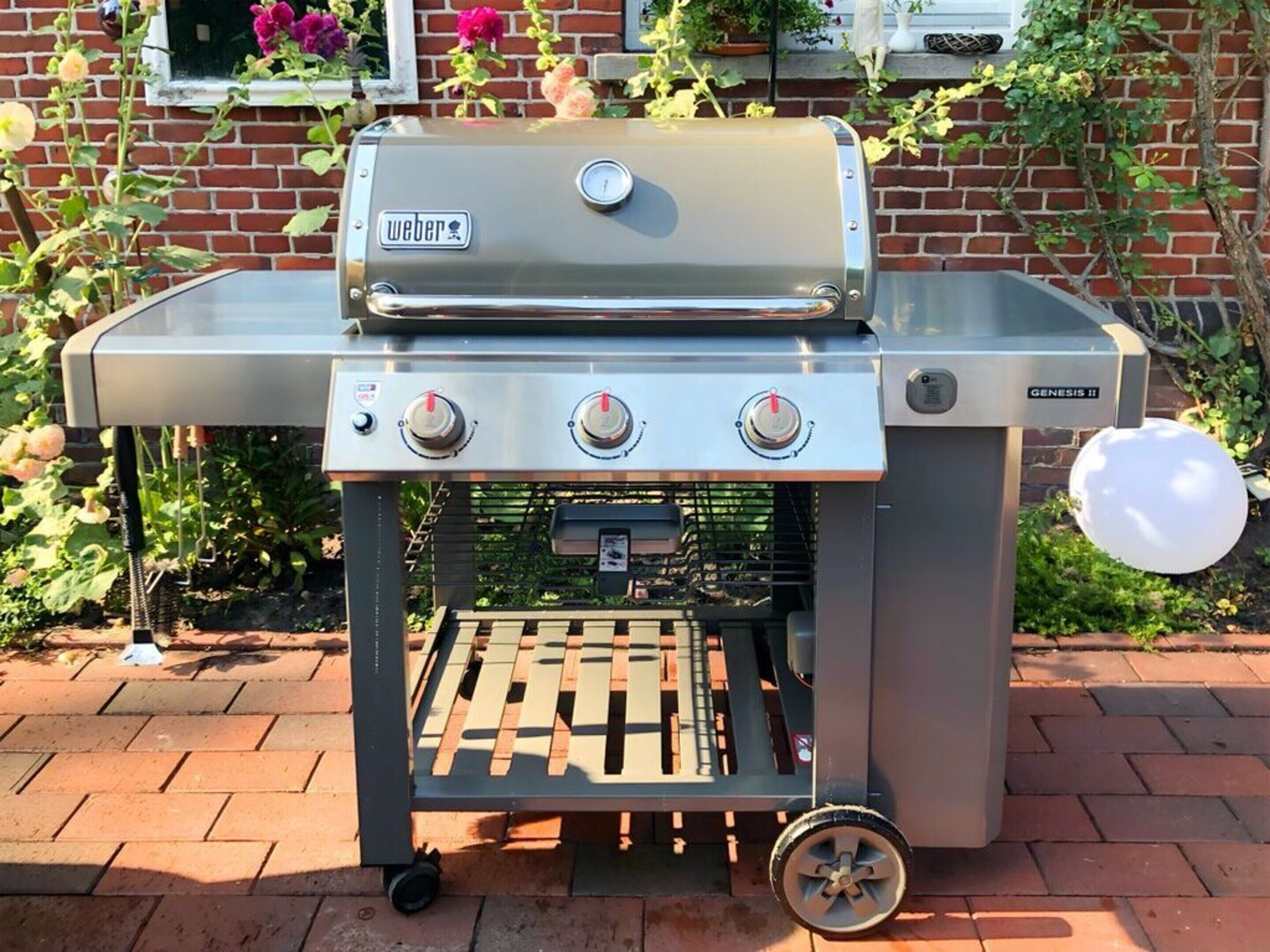 A Weber Genesis II portable grill with three control knobs, a digital display, and a built-in thermometer.