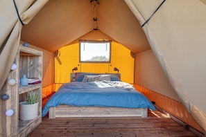 Ein Zelt mit Bett, Holzregalen und einem Fenster.