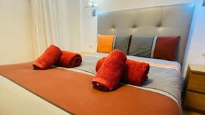 Una habitación de hotel con una cama, cabecera y mesita de noche.