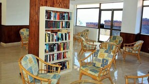 Una biblioteca con sillas de mimbre y una estantería llena de libros.