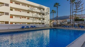 Un hotel con piscina, varios balcones y palmeras.