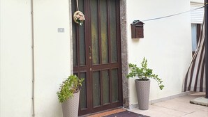A residential entrance with a brown door, a small mailbox, and two potted plants. - Apartment in Matera Near Historic Center (Matera)