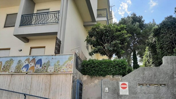 A residential building with a blue gate, a no entry sign, and a mural on the wall. - Apartment in Matera Near Historic Center (Matera)