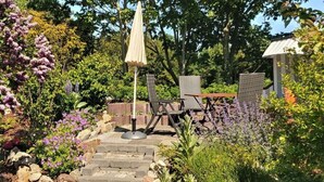 Eine Gartenpatio mit einem gepflasterten Weg, Gartenmöbeln und üppiger Bepflanzung.