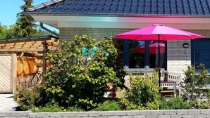 Ein Haus mit Ziegeldach und Backsteinfassade, mit einem pinkfarbenen Sonnenschirm.