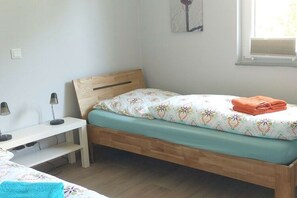 A single bed with a wooden headboard, a bedside table, and a lamp. - Lovely Apartment in Borkum (Borkum)
