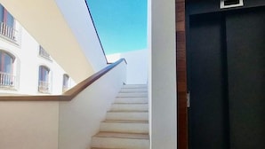 A staircase leading to a dark door, with a white wall and a window on the left. - Apartment in Puerto del Rosario Near Playa Chica (Puerto del Rosario)