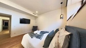 A bedroom with a bed, a TV mounted on the wall, a chair, and a hanging light fixture. - Apartment in Puerto del Rosario Near Playa Chica (Puerto del Rosario)