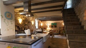 A modern kitchen with a central island, stone walls, and a staircase leading to an upper level. - House of Olives Comfortable Holiday Residence (Dobrinj)