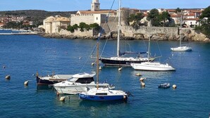 A harbor with several boats docked, a prominent building with a dome, and a backdrop of residential houses. - House of Olives Comfortable Holiday Residence (Dobrinj)