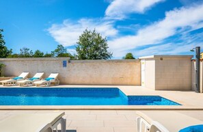 Una piscina con sillas de descanso y una pared con un letrero.
