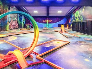 Un ambiente interno dal design futuristico, caratterizzato da una grande struttura circolare e da un murale con soggetti spaziali.