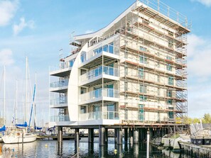 Un edificio de varios pisos en construcción con vista al agua, que cuenta con balcones y ventanas amplias.