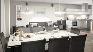 A modern dining area with a white table set for four, surrounded by dark chairs. - Holiday Home in Wendtorf (Wendtorf)