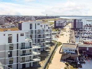 Una zona residenziale costiera con edifici moderni, un porto turistico e una vista libera sul mare.