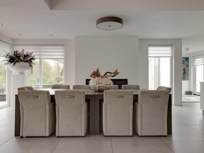 Un comedor moderno con una mesa central, cuatro sillas tapizadas y un jarrón decorativo.